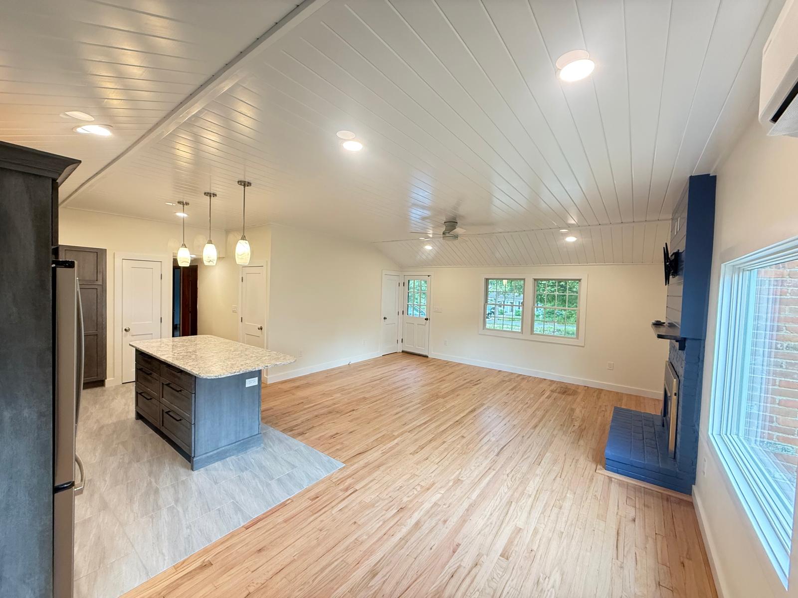 Living room with shiplap ceiling, custom fireplace and refinished floors