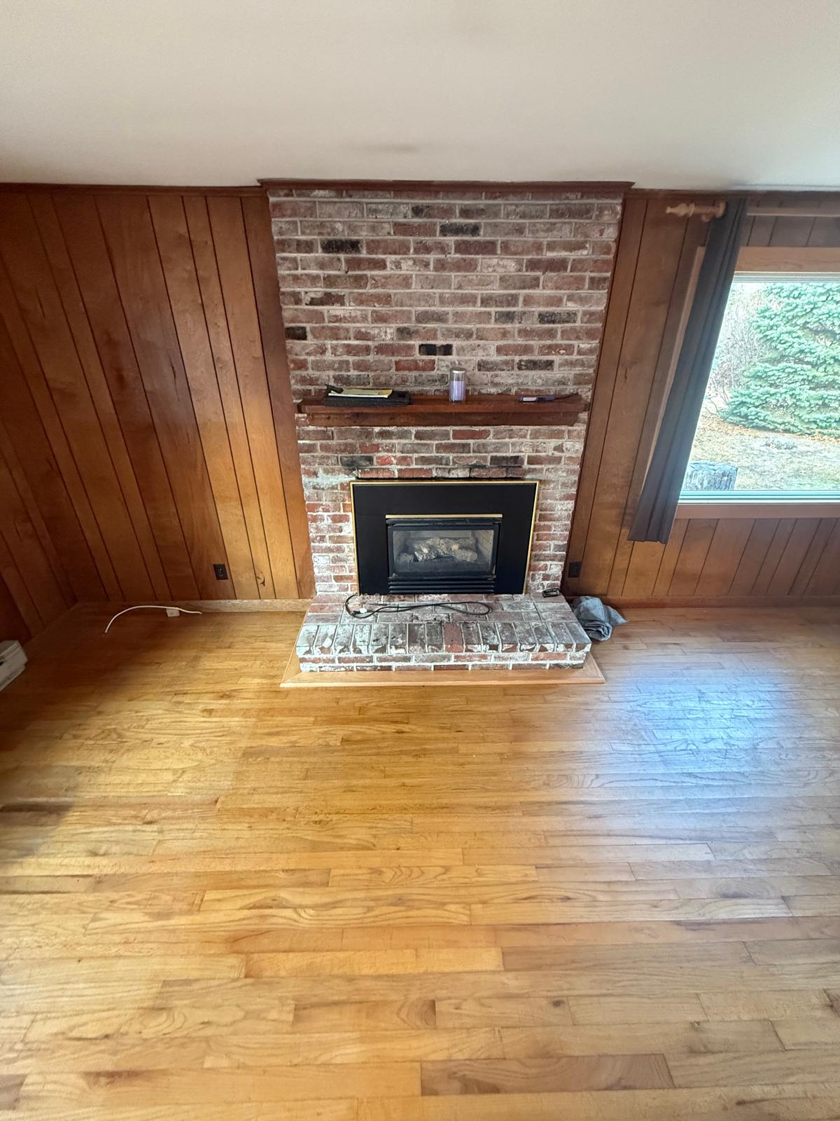 Original brick fireplace with dark wood paneling